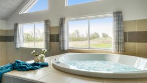 a large bath tub in a bathroom with windows at Villavilla 441 - Grenå Strand, Østjylland in Grenå