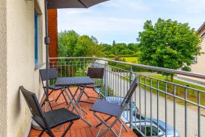 a balcony with three chairs and an umbrella at Ferienwohnung Katharina OG in Wohlenberg