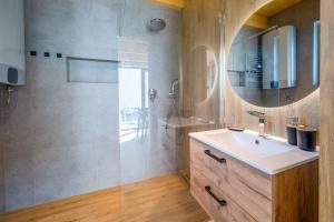 a bathroom with a sink and a shower with a mirror at PATIO APARTAMENTY in Łagów