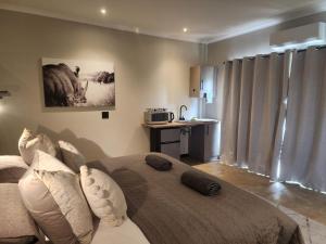 a bedroom with a bed with pillows and a kitchen at Charlen's Rest in Windhoek +29 photos