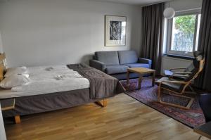 a bedroom with a bed and a couch and a chair at Ronneby Cityhotell in Ronneby