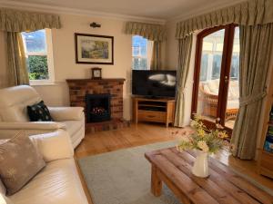 a living room with a couch and a tv and a table at Oak Tree Cottage, Charming, Rural New Forest Home in Boldre