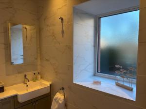 a bathroom with a window and a sink and a mirror at Stable Cottage in Lockerbie +20 photos