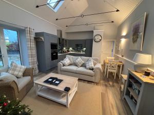 a living room with two couches and a table at Stable Cottage in Lockerbie
