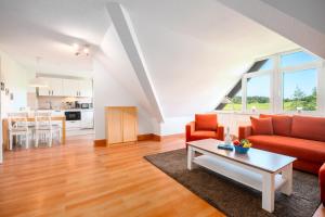 a living room with a red couch and a table at Strandhaus Lobbe, Mohnblume Nr 20 - Bade- & Saunawelt täglich inklusive in Middelhagen