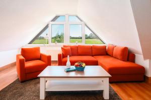 a living room with an orange couch and a table at Strandhaus Lobbe, Mohnblume Nr 20 - Bade- & Saunawelt täglich inklusive in Middelhagen