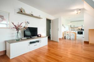 a living room with a flat screen tv on a cabinet at Strandhaus Lobbe, Mohnblume Nr 20 - Bade- & Saunawelt täglich inklusive in Middelhagen