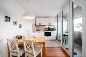 a kitchen and dining room with a wooden table and chairs at Strandhaus Lobbe, Mohnblume Nr 20 - Bade- & Saunawelt täglich inklusive in Middelhagen +15 photos
