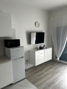 a living room with white furniture and a flat screen tv at Monami- Apartman Mia in Vodice