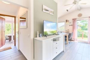 a living room with a desk with a tv on it at Wattkueken in Simonsberg +18 photos