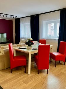 a living room with a table and red chairs at Bytom Syrah in Bytom
