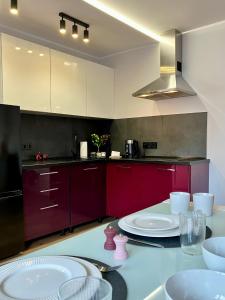 a kitchen with red cabinets and white plates on a table at Bytom Syrah in Bytom