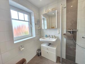 a white bathroom with a sink and a shower at Ferienwohnung Meerglück in Norden +25 photos