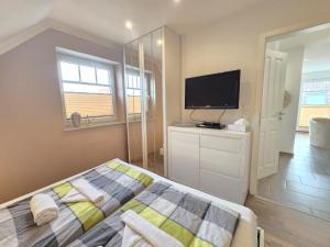 a bedroom with a bed and a flat screen tv at Ferienwohnung Meerglück in Norden