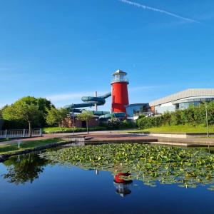 a lighthouse and a pond in front of a building at Ferienwohnung Meerglück in Norden