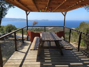 a wooden table and chairs on a deck with a view of the ocean at CAMPING MONTE ORTU in Lumio