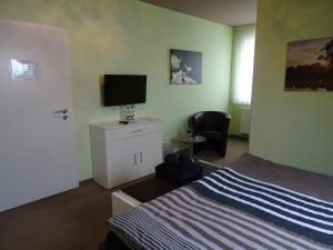 a bedroom with a bed and a flat screen tv at Wohlfühl Hotel & Pension am Birnengarten - Ruhige Zimmer mit Bad & WLAN in Magdeburg +29 photos
