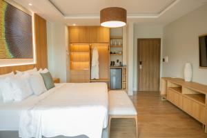 a bedroom with a large white bed and a kitchen at Hotel Equinocios Executive in Barcarena