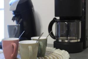 three coffee cups sitting on a table next to a coffee maker at Le nid des Huttes in Gravelines