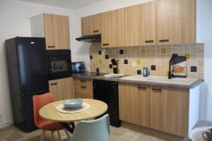 a kitchen with a small table and a black refrigerator at Le nid des Huttes in Gravelines