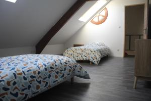 a attic bedroom with two beds and a window at Le nid des Huttes in Gravelines
