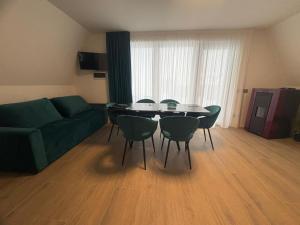 a living room with a green couch and a table and chairs at Panoramic Nicolas in Borsa