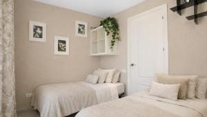 a bedroom with two beds with white sheets at Spacious Duplex in Sitges with Sea Views, Terrace & Free Parking Area in Sitges