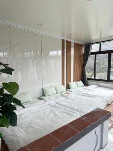 a large white bed in a room with a window at Holly House Mộc Châu in Mộc Châu +3 photos