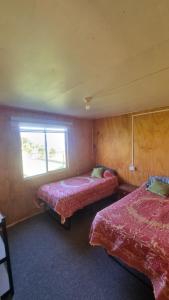 a room with two beds and a window at cabañas cubero in Gualaihue