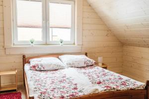 a bed in a room with two windows at Orawska Sielanka in Roztoki