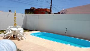 a swimming pool with chairs next to a white fence at Casa temporada aracaju sergipe in Aracaju