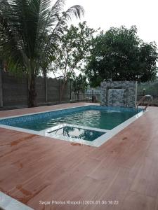 a swimming pool in a yard with a wooden floor at River Garden Guest House in Jambhulpāda