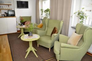 a living room with green chairs and a table with a vase at Ronneby Cityhotell in Ronneby