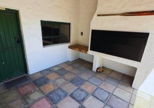 a room with a flat screen tv and a door at Fisherman's Cottages at Blombosch Game Farm in Yzerfontein