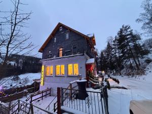a house with its lights on in the snow at Antique Hotel Am Bahndamm in Wallendorf