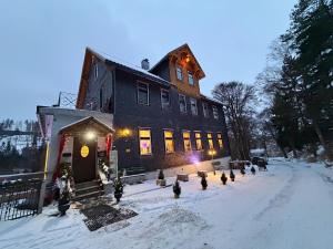 a building in the snow with christmas trees in front at Antique Hotel Am Bahndamm in Wallendorf