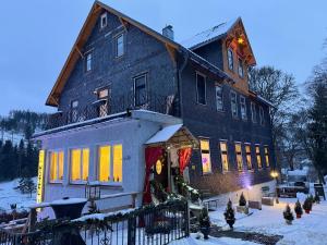 a large house with christmas lights on it in the snow at Antique Hotel Am Bahndamm in Wallendorf