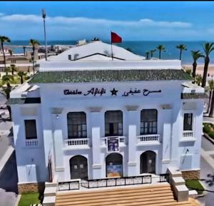 a white building with a sign on it next to the ocean at Appart Ennakhil 4 avenue mohamed 6 in El Jadida