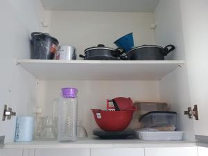 a kitchen shelf with pots and pans and a bottle at Flats Mundos Golfinhos in Pipa +21 photos