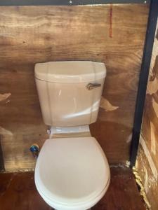 a white toilet in a room with a wooden wall at Okatjongoro Campsite in Gkamboro Settlement