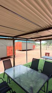 a glass table and chairs under a tent at Okatjongoro Campsite in Gkamboro Settlement