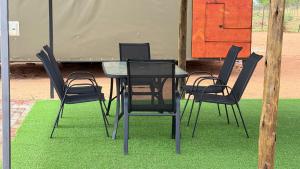 a black table and chairs on green grass at Okatjongoro Campsite in Gkamboro Settlement +24 photos