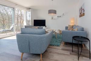 a living room with two blue chairs and a tv at Haus Waldidyll, Vergissmeinnicht - Bade- & Saunawelt täglich inklusive in Ostseebad Sellin