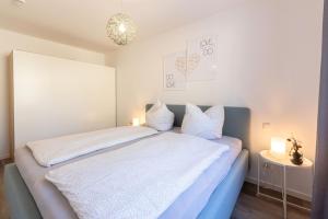 a bedroom with a bed with white sheets and pillows at Haus Waldidyll, Vergissmeinnicht - Bade- & Saunawelt täglich inklusive in Ostseebad Sellin