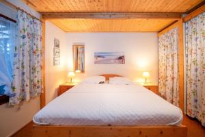 a bedroom with a white bed with two lamps at Ferienhaus am Strand 92 - Bade- & Saunawelt täglich inklusive in Baabe +9 photos