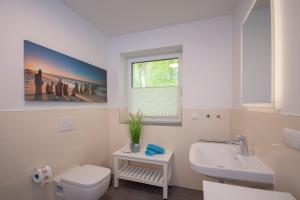 a bathroom with a sink and a toilet and a window at Haus Waldidyll, Küstenflair - Bade- & Saunawelt täglich inklusive in Ostseebad Sellin +40 photos