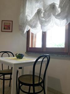 une table avec deux chaises et une fenêtre avec des rideaux dans l'établissement Rosa's House - zona ospedaliera, à Cagliari