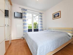 a bedroom with a bed and a tv and a window at Ostseebrise - Bade- & Saunawelt täglich inklusive in Thiessow