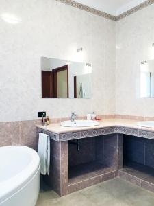 Rosa's House - zona ospedaliera في كالياري: حمام به مغسلتين وحوض استحمام ومرآة