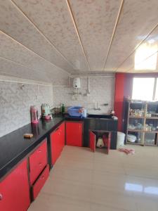 a kitchen with red cabinets and a black counter top at Tenzing Homestay in Kalimpong